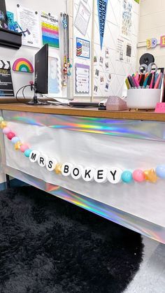 a desk with a name on it in the middle of a school room filled with supplies