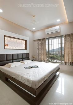 a large bed sitting in the middle of a bedroom next to a window with curtains