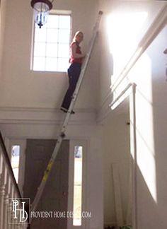 a man is standing on a ladder in the middle of a room with sunlight coming through the window