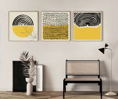 three abstract paintings hang on the wall above a black chair in a white living room