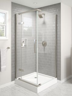 a bathroom with a walk in shower next to a white tiled wall and flooring