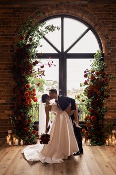 a bride and groom kissing in front of an arched window