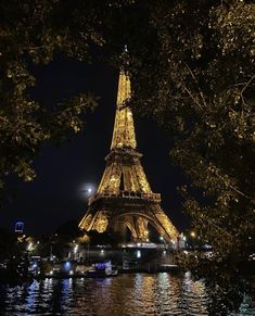 the eiffel tower lit up at night with lights reflecting in the water below