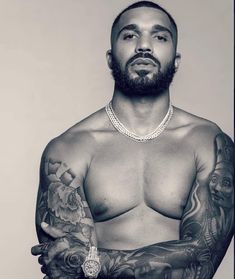 a black and white photo of a shirtless man with tattoos on his arms, chest and arm