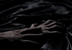 a black and white photo of someone's hand on a bed with dark sheets