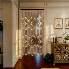 a living room with a wooden floor and white walls covered in beaded curtains on the door