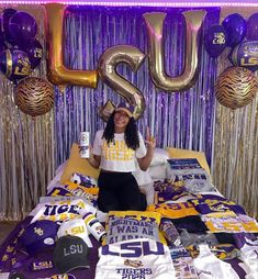 a woman sitting on top of a bed in front of foil streamers and balloons