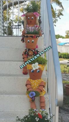 three clay pots with flowers and plants on them are sitting on the steps next to a set of stairs