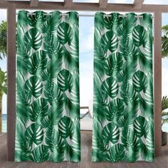 a green and white tropical print curtain with palm leaves on the outside, in front of a window