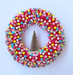 a christmas wreath made with beads and a small tree in the center on a white surface