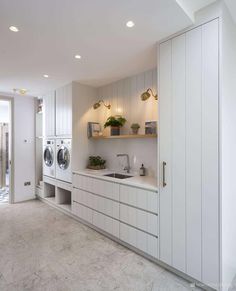 a washer and dryer in a white laundry room with open shelving on the wall