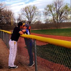 two baseball players leaning on the fence to hug each other