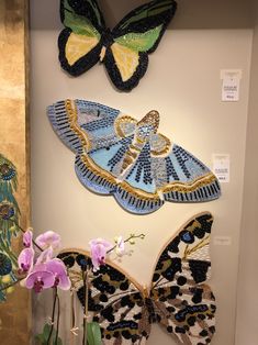 three butterflies are hanging on the wall next to flowers