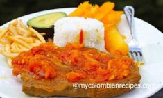 a white plate topped with meat, rice and veggies next to a fork