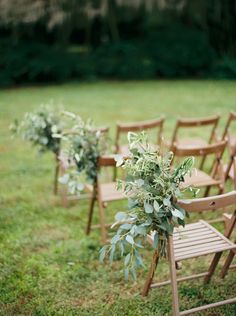 an outdoor ceremony with wooden chairs and greenery