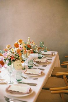 the table is set with place settings and flowers in glass vases on each side