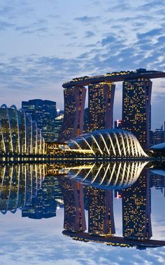 the skyline of singapore is reflected in the water at night with skyscrapers lit up