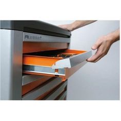 a man is opening an orange file cabinet