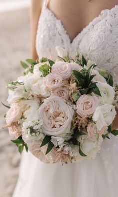 a bride holding her bouquet on the beach