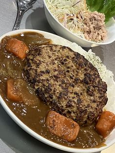 two plates with meat, gravy and carrots on them sitting on a table