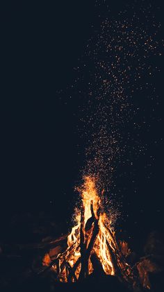 two people standing in front of a campfire with their hands up and arms raised