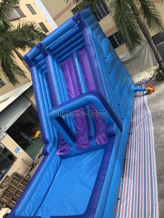 an inflatable water slide is set up on the side of a building with palm trees