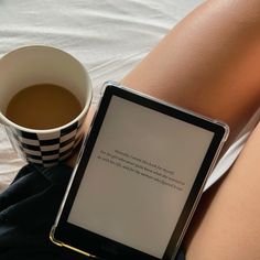 a woman's legs with a cup of coffee and an electronic device on her lap