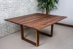 a wooden table sitting in front of a brick wall next to a potted plant