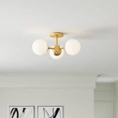 three white balls are hanging from the ceiling in this modern living room with two black and white paintings