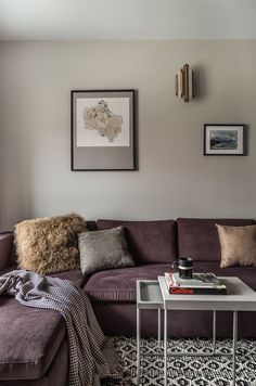 a living room with a couch, coffee table and pictures on the wall above it