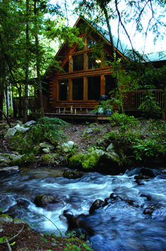 a log cabin sits on the edge of a river