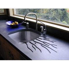 a kitchen sink sitting under a window next to a bowl of fruit on top of a counter