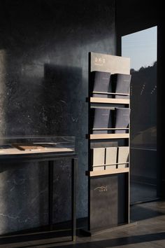 a book shelf with several books on it next to a table and window in an empty room