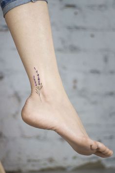 a woman's foot with a small flower tattoo on it