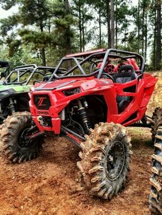 four atv's are parked in the dirt near some trees