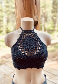 a mannequin wearing a black crochet halter top on a wooden table