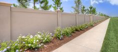 a fence with flowers growing on it next to a sidewalk