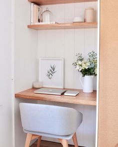 a desk with a laptop on top of it and some flowers in the vase next to it