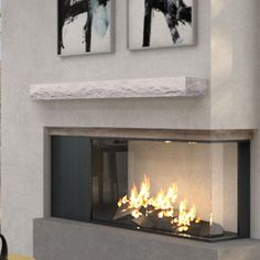 a fire place in a living room with two pictures on the wall and one is lit