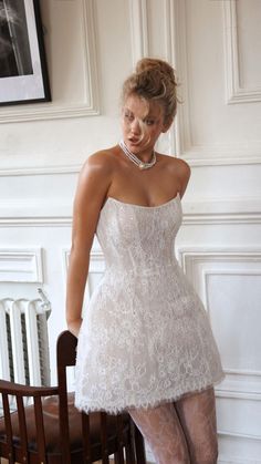 a woman in a short white dress standing on a chair