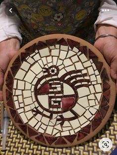 a person is holding a plate made out of mosaic tiles and glass with the letter e on it