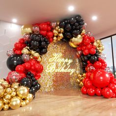 an arch made out of balloons with the words happy birthday in gold, black and red