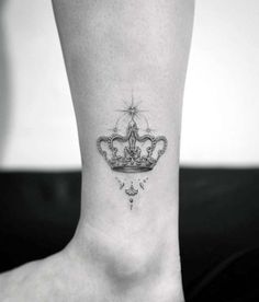 a woman's foot with a crown tattoo on the side of her leg and a star above it