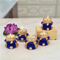 four blue and gold candles sitting on top of a table next to a purple flower