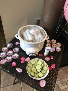 a table topped with cucumbers and cupcakes next to a crock pot