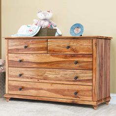 a wooden dresser with two stuffed animals on it's top and the bottom drawer