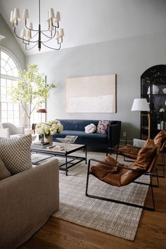 a living room filled with furniture and a chandelier hanging from the ceiling above