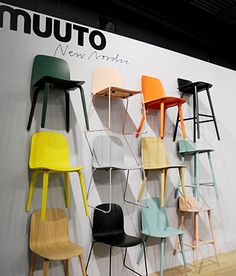 several different colored chairs are on display in front of a wall with the word muuto next to it