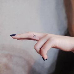 a woman's left hand with a small tattoo on the middle finger and an arrow