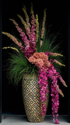 a vase filled with lots of flowers on top of a table next to a wall